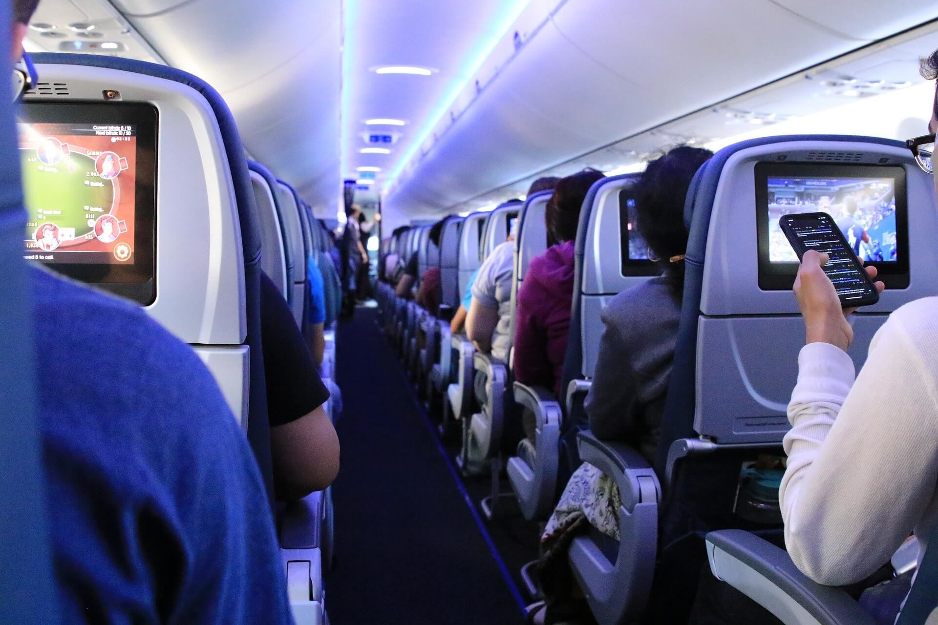 Passangers on an airplane, the view is down the centre aisle.