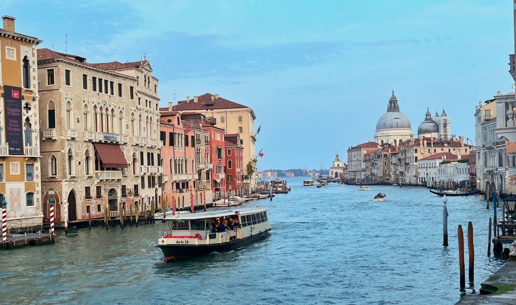 An image of a Vaporetto water taxi in Venice with the Basilica of Santa Maria della Salute in the background. 